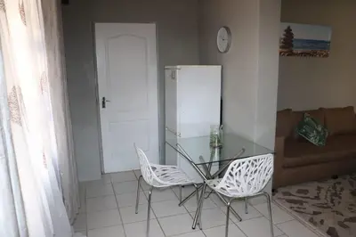 a dining room with a glass table and two chairs at Unitrainview guest house in Pretoria