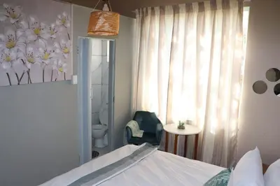 a bedroom with a bed and a bathroom with a window at Unitrainview guest house in Pretoria