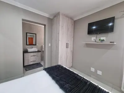 a bedroom with a bed and a tv on the wall at Emerald Guesthouse in Kempton Park