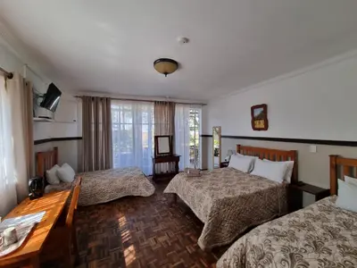 a hotel room with two beds and a table at Emerald Guesthouse in Kempton Park