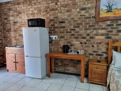 a kitchen with a white refrigerator next to a brick wall at Emerald Guesthouse in Kempton Park