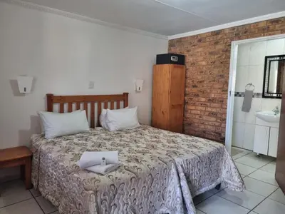a bedroom with a bed with a cross on it at Emerald Guesthouse in Kempton Park