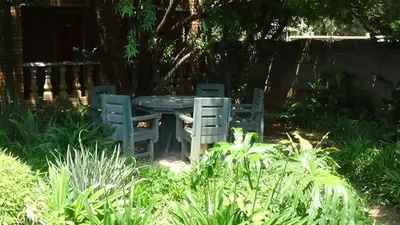 two chairs and a table in a garden at Emerald Guesthouse in Kempton Park