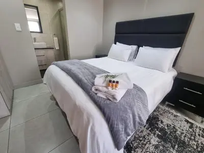 a bedroom with a large bed with towels on it at Emerald Guesthouse in Kempton Park