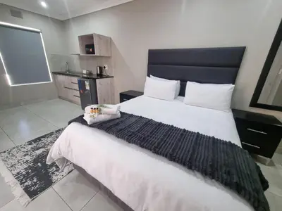 a bedroom with a large bed with a black headboard at Emerald Guesthouse in Kempton Park