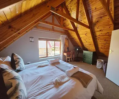 a large bed in a room with a wooden ceiling at Mountain View Cottage in Dullstroom