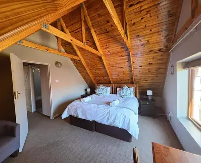 a bedroom with a large bed with a wooden ceiling at Mountain View Cottage in Dullstroom