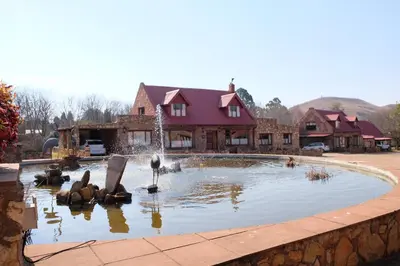 a swimming pool with a fountain in front of a house at Mountain View Cottage in Dullstroom