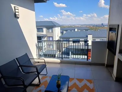 a balcony with chairs and a view of a building at Spacious 2 Bedroom Apartment in Carslwald, Midrand - Business and Family friendly - 2 Elizabeth Place in Midrand