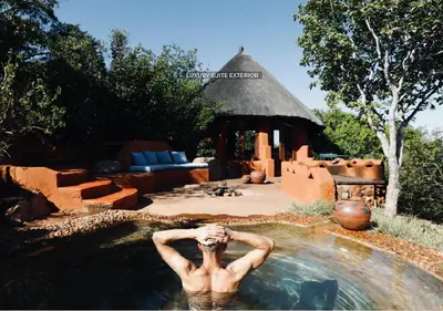 a man in a pool of water in front of a house at Leshiba Wilderness in Louis Trichardt
