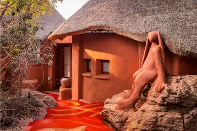 a house with a thatch roof and a red floor at Leshiba Wilderness in Louis Trichardt