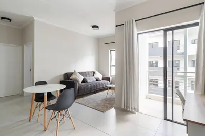 a living room with a couch and a table and chairs at The Blissful Abode by BK Hospitable in Midrand