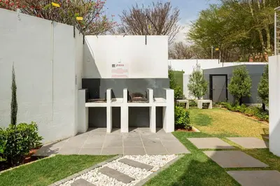 a fireplace in a garden with a white wall at The Blissful Abode by BK Hospitable in Midrand