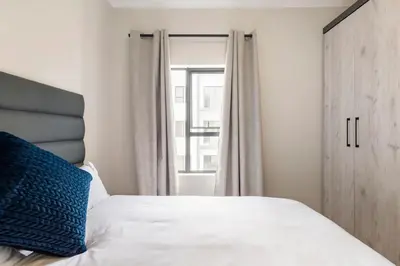a bedroom with a bed with a blue pillow and a window at The Blissful Abode by BK Hospitable in Midrand