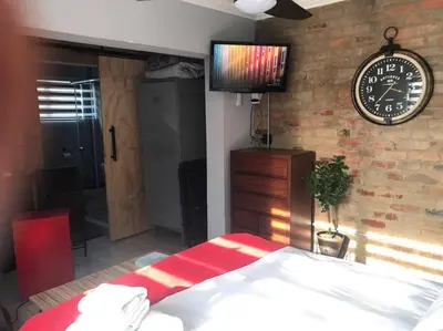 a bedroom with a bed and a clock on a brick wall at Red Lotus Studio Pta East-No Loadshedding in Pretoria