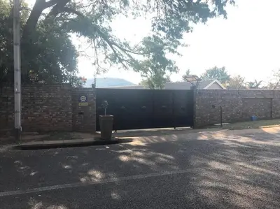 a fence with a black gate in front of a house at Red Lotus Studio Pta East-No Loadshedding in Pretoria