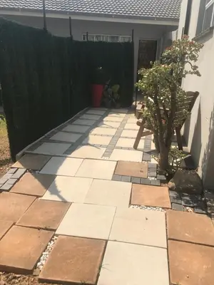 a garden with a stone walkway next to a fence at Red Lotus Studio Pta East-No Loadshedding in Pretoria