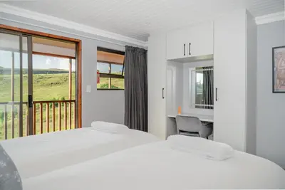 a bedroom with a bed and a desk and a window at Log Cabin Moonlight Meadows Dullstroom. in Dullstroom