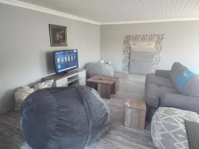 a living room with a couch and a tv at Log Cabin Moonlight Meadows Dullstroom. in Dullstroom
