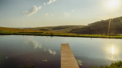 a wooden dock in the middle of a lake at Log Cabin Moonlight Meadows Dullstroom. in Dullstroom