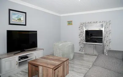 a living room with a couch and a television at Log Cabin Moonlight Meadows Dullstroom. in Dullstroom