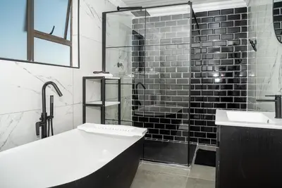 a bathroom with a tub and a sink and a shower at Log Cabin Moonlight Meadows Dullstroom. in Dullstroom