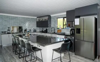 a kitchen with a large island with bar stools at Log Cabin Moonlight Meadows Dullstroom. in Dullstroom