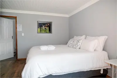 a bedroom with a bed with white sheets and pillows at Log Cabin Moonlight Meadows Dullstroom. in Dullstroom