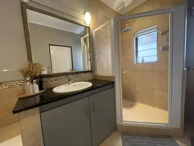 a bathroom with a sink and a shower with a mirror at Khululeka Safaris Lodge in White River
