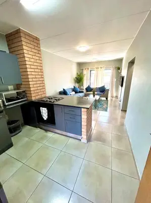 a kitchen with a stove and a living room at The Place @ Mall of Africa in Midrand