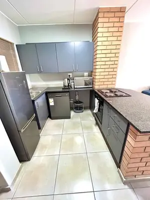 a small kitchen with blue cabinets and appliances at The Place @ Mall of Africa in Midrand