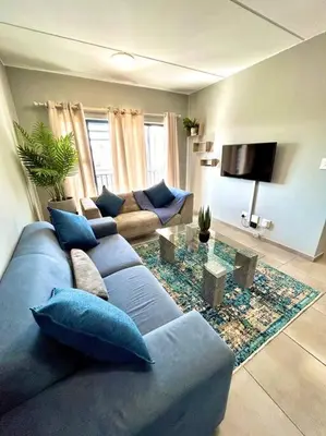 a living room with a blue couch and a table at The Place @ Mall of Africa in Midrand