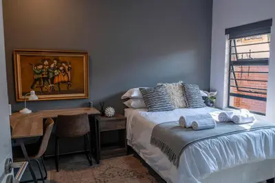 a bedroom with a desk and a bed with towels on it at Rand Corner Crib in Pretoria