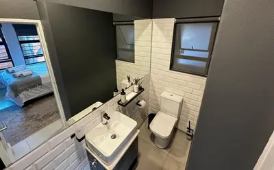 a bathroom with a sink and a toilet and a mirror at Rand Corner Crib in Pretoria