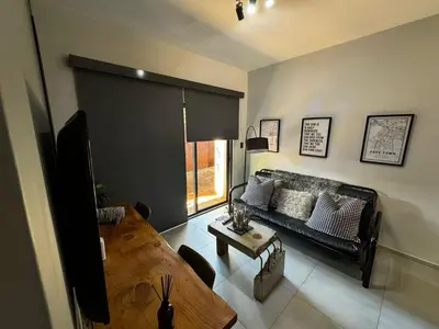 a living room with a black couch and a table at Rand Corner Crib in Pretoria