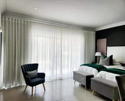 a bedroom with a large bed and a chair at La Chambre Manor House in Nelspruit