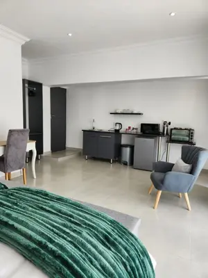 a bedroom with a living room and a kitchen at La Chambre Manor House in Nelspruit
