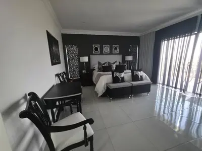 a black and white bedroom with a bed and a desk at La Chambre Manor House in Nelspruit