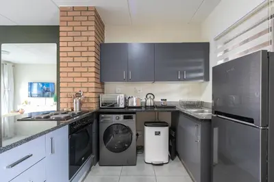 a kitchen with black cabinets and a washer and dryer at Modern 2 bed apartment, Secure estate in Midrand