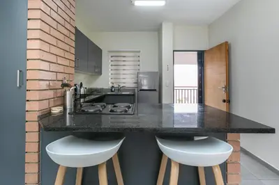 a kitchen with a counter with two white stools at Modern 2 bed apartment, Secure estate in Midrand