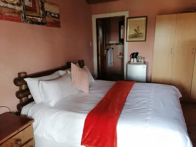 a bedroom with a large white bed with a red blanket at Kwena Maribane Lodge in Erasmus