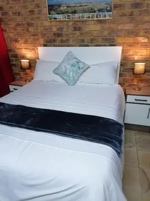 a large white bed in a room with two lamps at Kwena Maribane Lodge in Erasmus