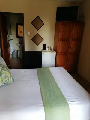 a bedroom with a white bed with a green blanket at Kwena Maribane Lodge in Erasmus