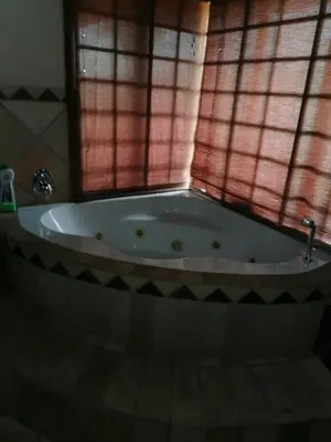 a bath tub in a bathroom with a window at Kwena Maribane Lodge in Erasmus