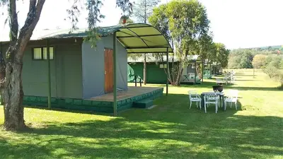 a small house with a table and chairs in a yard at Sabie River Camp in Sabie