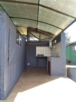 an outdoor kitchen with a roof over a garage at Sabie River Camp in Sabie