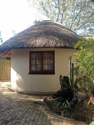 a small white house with a thatched roof at Harties Lodge - Private Suite in Hartbeespoort