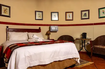 a bedroom with a bed and a table with chairs at Harties Lodge - Private Suite in Hartbeespoort