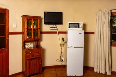 a kitchen with a refrigerator and a microwave and a tv at Harties Lodge - Private Suite in Hartbeespoort