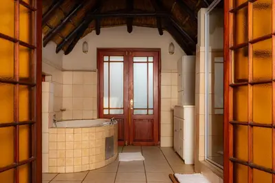 a bathroom with a bath tub and a wooden door at Manor House at Harties Lodge - Meerhof in Hartbeespoort